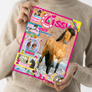 Person in beigefarbenem Strickpullover hält eine Ausgabe des Magazins „Lissy“ mit pinkem Rand. Auf dem Titelbild ein braunes Pferd mit schwarzer Mähne im Lauf, Hintergrund unscharf. Sichtbare Texte: „Coole Punkte Appaloosa“, „Teste dein Lissy-Wissen!“, „Fotoroman: Lale in Gefahr“, „2 bezaubernde Poster!“, „Spannender Comic“. Mehrere kleine farbige Cartoon-Tiere und Fotos von Pferden sind als Zusatzabbildungen platziert.
