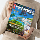 Person mit beigefarbenem Strickpullover hält ein Magazin mit dem Titel „REISE & PREISE – Den Traumurlaub perfekt planen“ vor neutralem Hintergrund; auf dem Cover eine Küstenlandschaft mit türkisblauem Meer, weißen Felsen und grünen Bäumen. Sichtbare Texte: „Queensland Australiens Naturwunder“, „Den Sommer verlängern“, „19 traumhafte Ziele für die Nebensaison“, sowie Ortsnamen „Istrien“, „Bangkok“, „Irland“ und „Marokko“.