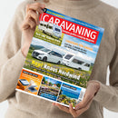Hellbeige gekleidete Person hält ein Magazin mit dem Titel „CARAVANING – Europas großes Camping-Magazin“. Das Cover zeigt zwei weiße Wohnwagen vor einer Wiesenlandschaft mit blauem Himmel, dazu gelbe und weiße Überschriften wie „Neu! Knaus Nordwind“, „Test LMC Videro 510 E“ und „CARAVANS FÜR GROSSE“. Unten kleinere Bilder zu Themen wie Kühlung, Reisen und Campingplätzen in Istrien.
