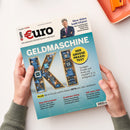 Zwei Hände halten das Magazin „€uro – Das Magazin für Wirtschaft und Geld“, Ausgabe 7/2026, vor hellem Hintergrund. Titelthema: „GELDMASCHINE KI – Der große Praxistest“ in großen Buchstaben mit Leiterplattenstruktur im Schriftzug „KI“. Weitere sichtbare Texte: „So legen Private und Profis mit ChatGPT & Co erfolgreich an“, „Mega-Börsengänge“, „Dividenden-König“, „250 Jahre USA“. Oben ein Porträt einer männlichen Person im Anzug mit gekreuzten Armen.