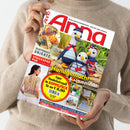 Helle, langärmlig gekleidete Person hält das Magazin „Anna“ mit rotem Titelkopf in den Händen; auf dem Cover erscheinen drei gehäkelte Vögel in bunten Streifenmustern, eine Frau in gestricktem Oberteil, Garnknäuel und Handarbeitsprojekte. Sichtbare Texte: „Selbstgemachte Unikate“, „Handgemacht & sommerleicht“, „Strickspaß pur bis Größe 54“, „Super Handarbeitsspaß im Doppelpack“.