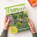 Titelblatt der Gartenzeitschrift „Mein schöner Garten“, Ausgabe Juni 2025, mit grün-weißem Schriftzug und Foto eines blühenden Gartens mit Gartenmöbeln. Textaussagen auf dem Cover u. a.: „Richtig düngen leicht gemacht“, „Unsere 50 schönsten Ideen für Ihren Sommergarten“, „12 Seiten Gartenpraxis im Juni“ und „Duftende Stauden entdecken“. Gehalten von zwei Händen über heller Oberfläche mit orangefarbenem Objekt rechts oben.