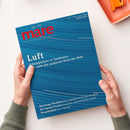 Magazin „mare – Die Zeitschrift der Meere“, Ausgabe Nr. 176, wird von zwei Händen gehalten; Titel in roter Schrift auf blauem Hintergrund mit wellenförmigem Linienmuster. Hauptüberschrift „Luft – Schnupperkurs in Tasmanien. Hier weht die sauberste Brise der Welt“ sowie weitere Themen: „Meer enge Dschibuti“, „Die Splash-Formel“ und „Strandfußball Rio in Rostock“; im Hintergrund beige Oberfläche und orangefarbene Schale mit Büroklammern.