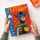 Titelseite des Kindermagazins „ZEIT leo“ mit rotem Hintergrund, zentralem Foto einer Ziege mit blauer Superheldenmaske und -cape. Gelbe Überschrift „Die Superkraft der Tiere“, daneben gelber Stern mit Text „So machen dich Ziege, Huhn und Hase stark“. Linker blauer Rand mit Logo „DIE ZEIT“, Zeichnung einer Comicfigur mit Text „Das Kindermagazin mit Greg“, sowie weiteren Schlagzeilen zu „WM-Stars“, „Spurensuche“ und „Tempo 300“. Zwei Hände halten das Heft.