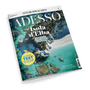Magazin-Cover: ZEIT SPRACHEN ADESSO, malerische Luftaufnahme einer Küste mit türkisblauem Wasser und Felsen. Schlagzeile: Isola d'Elba – So lebt es sich auf der coolsten Insel Italiens!