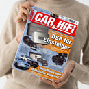 Person mit hellbeigem Strickpullover hält Zeitschrift „CAR & HIFI“ (Ausgabe 4/2026). Titel mit rotem Balken und weißer Schrift, orange hinterlegter Haupttext „DSP für Einsteiger“. Abgebildet sind mehrere Auto-HiFi-Komponenten wie Lautsprecher, Endstufen und Subwoofer sowie zwei Autos unten links. Weitere sichtbare Texte: „Neue Lautsprecher“, „Topmodern oder traditionell“, „Unauffällig oder maximaler Aufwand“.