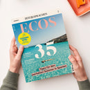 Magazin „ECOS“ der Reihe „ZEIT SPRACHEN“ in deutscher Sprache, gehalten von einer Person mit hellen Händen über heller Fläche; Titel zeigt türkisblaues Meer mit schwimmender Person und Felsküste im Hintergrund. Aufdrucke: großes „35“, „Tipps für den perfekten Sommer in Spanien“, „EL ABANICO – Die Geheimnisse des Fächers“, „GASTRONOMÍA – Die Küche der Kanarischen Inseln“, gelber Kreis mit „GEWINNSPIEL Superstar Juanes in Berlin“.
