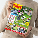Titelblatt des Magazins „selbst ist der Mann – Das Do-it-yourself-Magazin“ in gelbem und rotem Design, gehalten von einer Person mit hellbraunem Pullover. Hauptaufmacher: „Smarte Mäher ohne Draht“ mit mehreren abgebildeten Rasenrobotern auf grünem Rasen. Weitere sichtbare Textelemente: „Kleine Solaranlage“, „Camping-Urlaub“, „Kühl & schattig“, „Nutzgarten-Tipps“, „Wasser im Garten nutzen“ und mehrere kleine Fotos zu Heimwerker- und Gartenthemen.