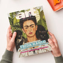 Titelblatt des Kunstmagazins „art“, Ausgabe Juli 2026, gehalten von zwei Händen vor hellem Hintergrund. Abgebildet ist ein Porträt von Frida Kahlo vor grünem Blattwerk mit einem schwarzen Affen und einer schwarzen Katze. Textaufschriften: „Jahrhundert-Schau in London“, „FRIDA KAHLO“, „Die Poetik des Raums: Vilhelm Hammershøi in Zürich“ und „Verrückte Genies? Ein Neurowissenschaftler über Kreativität“.