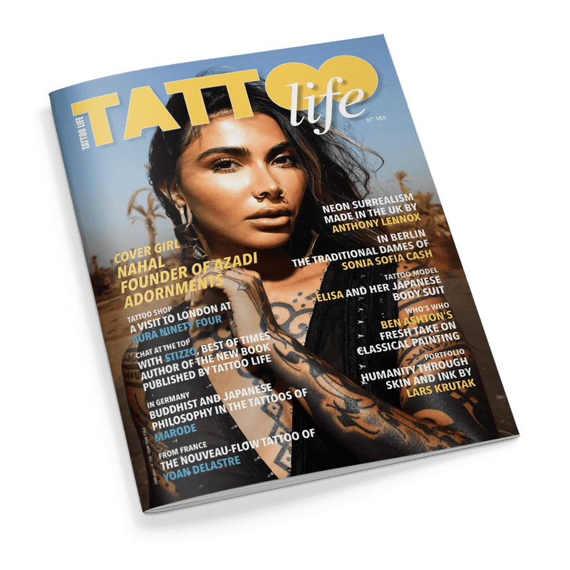 Titelbild der Zeitschrift „Tattoo Life“, Ausgabe 155, mit einer tätowierten weiblichen Person auf sandigem Untergrund; sichtbare Artikelüberschriften in gelber, weißer und blauer Schrift, u. a. „Cover Girl Nahal, Founder of Azadi Adornments“, „Neon Surrealism Made in the UK by Anthony Lennox“, „Japanese Philosophy in Ink“, Schriftzug „Tattoo Life“ oben mittig, Wort „Tattoo“ teilweise durch gelbes Herzsymbol überlagert.