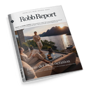 Titelblatt des Magazins „Robb Report“, Ausgabe Juli/August, mit weißem Rand und schwarzer Schrift. Haupttitel: „Luxus der Regeneration“. Abgebildet sind eine sitzende weiblich gelesene und eine stehende männlich gelesene Person in heller Freizeitkleidung auf einer Terrasse mit Glasgeländer, Blick auf See, Berge und Sonnenuntergang; auf dem Tisch stehen zwei Gläser und Schalen mit Snacks.