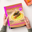 Schräg gehaltenes Magazin „FEINSCHMECKER“ mit orange-braunem Cover und pinker Typografie, von zwei Händen einer nicht näher bestimmbaren Person vor hellem Hintergrund gehalten. Sichtbare Texte: „Bodensee in Bestform“, „Mit Special Seiser Alm – Lokale, Hütten, Feinkost“, „Portugals Genuss-Oasen“ und „Neue Küchenwelten“; mittig liegt ein angerichtetes Fischgericht auf weißem Teller.
