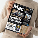 Magazincover „Mac Life“ wird von einer Person in beigem Pullover mit beiden Händen gehalten. Schwarzes Titelblatt mit großem weißen Schriftzug „Geniale Updates“ und Untertiteln zu Apple-Systemen 2026/27, iPhone-Geheimtipps und Kreativ-Apps. Abgebildet sind Apple-Geräte wie Laptop, iPhone, iPad und Maus, daneben kleinere Textblöcke in Weiß, Gelb und Blau mit weiteren Themenüberschriften.
