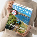 Magazincover der Ausgabe „ADESSO“ von „ZEIT SPRACHEN“, gehalten von einer Person in beigefarbenem Strickpullover vor neutralem Hintergrund. Das Titelbild zeigt einen blau-weiß-grauen Zug, der entlang einer Küste mit grünem Bewuchs und blauem Meer fährt. Sichtbare Texte: „FIT IN ITALIENISCH Wortschatz für die Zugfahrt“, „L’ITALIA IN TRENO“, „8 spektakuläre Zugstrecken für Ihren Urlaub“, „MUSICA“, „L’INTERVISTA“.