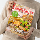 Person mit beigem Strickpullover hält eine Zeitschrift mit dem Titel „Landlust Einfach Hausgemacht – Mein Magazin für Haus und Küche“. Das Cover zeigt einen Teller mit gefüllten Schnitzeln und gemischtem Salat auf gedecktem Holztisch. Sichtbare Textüberschriften: „Gefüllte Schnitzel“, „Einfache Bistro-Küche“, „Frischer Spargel“, „Schnelle Küche“ und grünem Kreis mit „14 Seiten Erdbeer-Glück“.