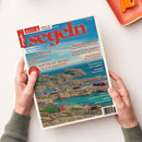 Titelbild der Zeitschrift „segeln“, Ausgabe Juni 2023. Zwei Hände halten das Magazin mit blauer Titelzeile und rotem Schriftzug „segeln“ über einem Foto einer felsigen Küstenlandschaft mit roten Holzhäusern am Wasser. Sichtbare Überschriften: „Ostsee Spezial“, „TOP YACHT AWARD“, „Bavaria Spezial“, „Segeln in der Lausitz“, „Ausrüstung“, sowie weitere Themen rund ums Segeln.