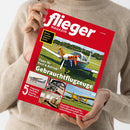 Weibliche Person im beigen Strickpullover hält ein schräg ausgerichtetes, rotes Magazin mit dem Titel „flieger MAGAZIN“. Das Cover zeigt ein Kleinflugzeug mit den Texten „Was ein Flugzeug wirklich kostet“, „Tipps für Kauf & Betrieb Gebrauchtflugzeuge“ und „5 Flugzeug-Porträts: Cessna, Piper & Co.“ sowie weitere Flugzeugfotos.