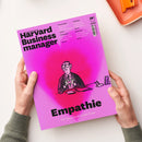Pink-magenta Zeitschrift „Harvard Business Manager“ mit schwarzem Titel, HBR-Logo und dem Titelthema „Empathie – Die Superkraft in der Krise“. Auf dem Cover stehen außerdem „Preise? Wie Sie mit Rabatten Umsatz pushen“, „Stakeholder Vertrauen aufbauen in Krisenzeiten“, „Einsteigerjobs KI kann Ihre Juniors nicht ersetzen“ und „Überlastung Lernen Sie, Ihren Kalender auszumisten“; zwei Hände halten das Magazin vor weißem Hintergrund, oben rechts liegt ein orangefarbenes Büroaccessoire.
