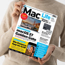 Eine Person im beigefarbenen Strickpullover hält ein schräg fotografiertes Cover der Zeitschrift „Mac Life“ mit weißem Hintergrund. Sichtbare Texte sind „iPhone Ultra: Apples große Pläne für das kommende Spitzenmodell“, „iPhone & iPad Life“, „macOS 27 Golden Gate“, „Die Kamera-App im Griff“ und „Über 100 Seiten Tests + Praxis“; abgebildet sind ein MacBook, ein iPhone, ein Mac mini und eine weibliche Person auf einem Smartphone-Display.