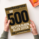 Goldbraunes Magazin „musikexpress“ mit schwarzer Titelzeile und der Aufschrift „DIE 500 BESTEN ALBEN ALLER ZEITEN“ in großer schwarzer und weißer Schrift; außerdem „Viel Stoff für deine Playlist!“, „TEIL 1“, „DAS GROSSE RANKING“ und „ALLE PLATTEN NEU GEHÖRT, NEU BEWERTET“. Zwei Hände mit grauen Strickärmeln halten das leicht schräg fotografierte Magazin vor weißem Hintergrund; oben rechts liegt ein orangefarbenes Objekt.