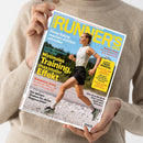 Eine weibliche Person in beigefarbenem Strickpullover hält ein schräg fotografiertes „RUNNERS WORLD“-Magazin mit weißem Rand. Das blaue Cover zeigt eine laufende Frau und trägt die Texte „Diese Salate machen wirklich schneller“, „Minimales Training, maximaler Effekt“, „Stabiler laufen: Home-Workout für eine starke Hüfte“ und „Trail-Special“.