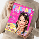 Weibliche Person im beigefarbenen Strickpullover hält eine schräg fotografierte, pinke Zeitschrift mit dem Titel „TOPModel FRIENDS Club“. Das Cover zeigt eine illustrativ dargestellte Figur mit dunklem Haar, großer violetter Schleife und Stern-Haarspangen sowie die Texte „Medienzeit: Sicher unterwegs im Internet mit Tipps von Jill“, „Beste-Freundinnen-Sommer“ und „Deine EXTRAS“.